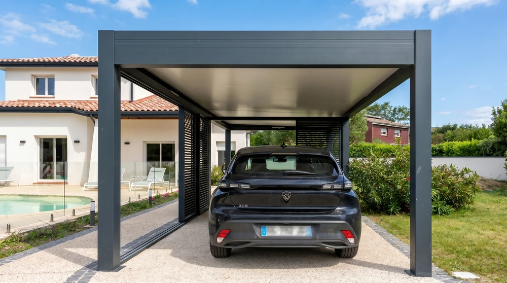 Carport aluminium anthracite moderne abritant une Peugeot 308 sombre, installé devant une villa contemporaine avec piscine