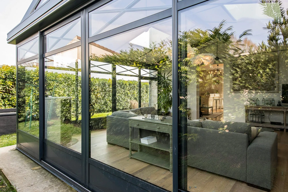 Extension de maison moderne avec véranda fermée à toiture plate, bardage aluminium anthracite RAL 7016